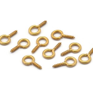 May include: Ten gold screw-in eye hooks with a small loop at the top. The hooks are arranged in a scattered pattern on a white background.