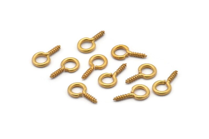 May include: Ten gold screw-in eye hooks with a small loop at the top. The hooks are arranged in a scattered pattern on a white background.