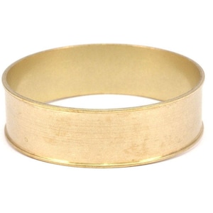 May include: A gold-colored metal ring with a smooth, slightly textured surface. The ring is about 1 inch wide and has a rounded edge.