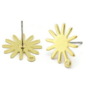May include: A pair of gold-tone sunburst stud earrings with a jump ring for attaching charms. The earrings have a simple, modern design.