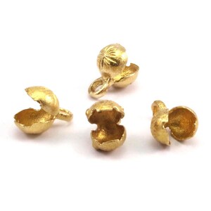 May include: Four gold-coloured metal end caps for jewellery making. The end caps are open on one side and have a small loop on the other side.