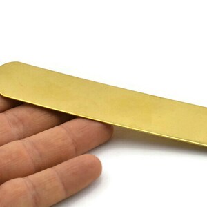 Op de afbeelding: Een lang, dun, plat stuk messing metaal. Het is een heldere gouden kleur en heeft een glad, gepolijst oppervlak.