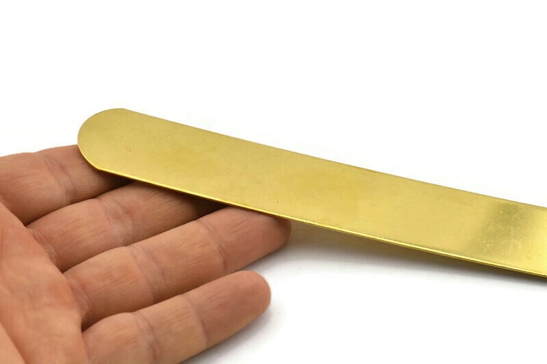 Op de afbeelding: Een lang, dun, plat stuk messing metaal. Het is een heldere gouden kleur en heeft een glad, gepolijst oppervlak.