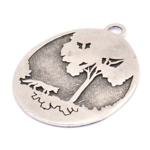May include: Silver oval charm with a cutout design of a tree. The charm has a textured surface and a loop for attaching to a necklace or bracelet.