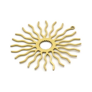 May include: A gold metal sunburst design with a small hole at the top and a gear-like circle in the center.