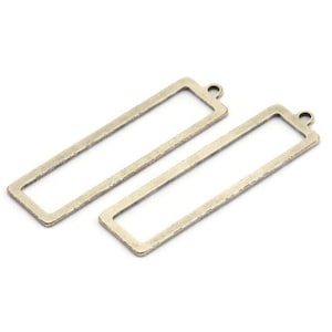 May include: Two gold-toned metal rectangular frame pendants with a loop at the top for hanging.