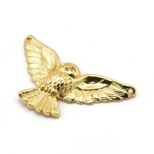 May include: Gold-colored metal owl charm with outstretched wings. The owl has a detailed design and is perfect for jewelry making or crafting.