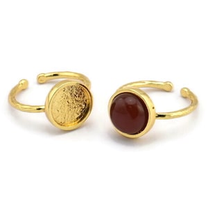 May include: Two gold adjustable rings with a round bezel setting. One ring has a red carnelian stone, the other ring has an empty bezel.