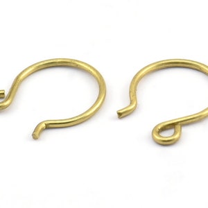 May include: Two gold-colored earring hooks. The hooks are made of metal and have a simple, rounded design.
