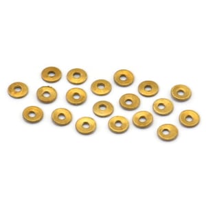 May include: A group of 18 gold-colored metal spacers, each with a circular shape and a hole in the center. The spacers are scattered on a white background.