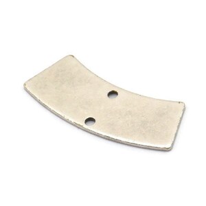 Puede incluir: Un componente metálico plateado y curvado con dos pequeños agujeros espaciados. La pieza tiene forma rectangular con bordes redondeados y una superficie ligeramente texturizada, sobre un fondo blanco.