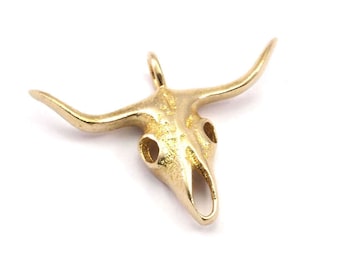 May include: A gold-colored pendant in the shape of a bull skull with horns.