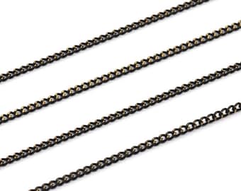 May include: Three strands of black chain with a gold undertone. The chain is a curb style with a flat, rectangular link.