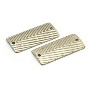 Pode incluir: Dois componentes retangulares de metal prateado com um padrão de chevron e dois furos. Os componentes são ligeiramente desgastados, sugerindo uma estética vintage ou artesanal. Ideal para a criação de joias.