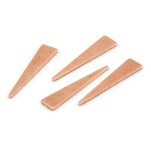 Puede incluir: Cuatro formas triangulares de metal de color oro rosa con textura martillada.