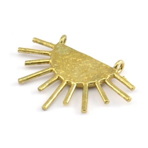 May include: A brass sunburst pendant with a half-circle base and radiating rays. The pendant has two small loops for attaching to a chain or other jewelry component. The pendant is approximately 1.5 inches wide.