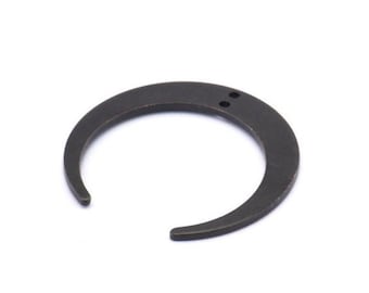 Può includere: Un anello in metallo nero a forma di mezzaluna con due piccoli fori nella parte superiore.