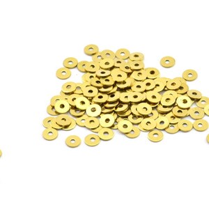 May include: A large pile of gold-colored metal washers. The washers are round with a hole in the center.