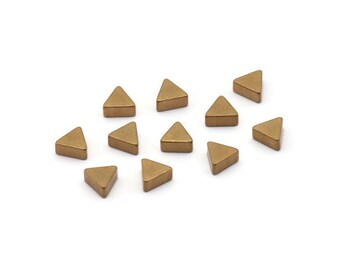 May include: A group of twelve small, gold-colored triangle-shaped ceramic tiles.
