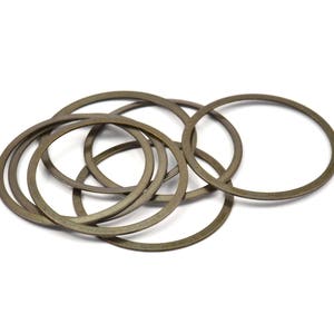 May include: A group of eight gold-colored metal rings, stacked and overlapping. The rings are smooth and have a shiny finish.