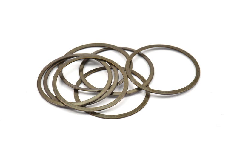 May include: A group of eight gold-colored metal rings, stacked and overlapping. The rings are smooth and have a shiny finish.