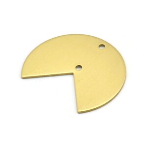 Puede incluir: Un círculo de metal de color dorado con una sección recortada y dos agujeros. El círculo tiene un diámetro de aproximadamente 5 cm.