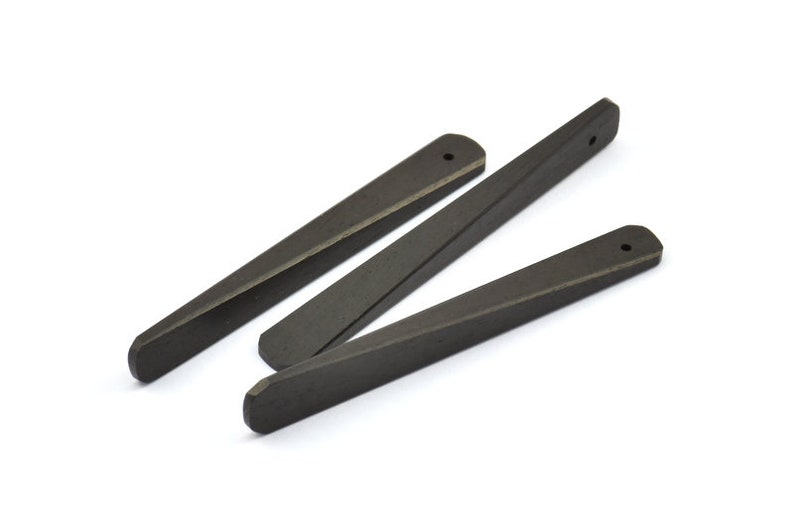 May include: Three black wooden tapered sticks with a small hole at the top of each stick.
