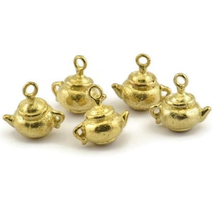 Könnte beinhalten: Fünf goldfarbene Teekannen-Anhänger mit einer Schlaufe zum Aufhängen. Die Anhänger sind etwa 2,5 cm hoch und haben ein detailliertes Design.