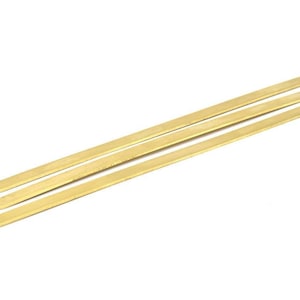 Puede incluir: Tres tiras de metal de color dorado, cada una con extremos redondeados, están apiladas una encima de la otra.