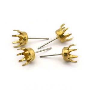 May include: Four gold-toned earring settings with prongs and posts. The settings are designed to hold a stone or other embellishment.