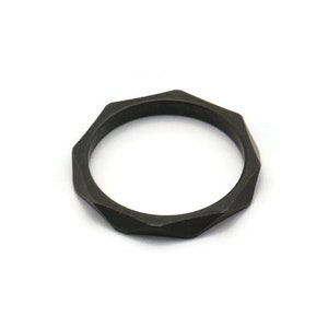 Puede incluir: Un anillo geométrico negro con un diseño facetado.