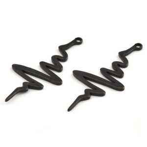 May include: Two black metal earring charms shaped like a stylized tree with a loop at the top.
