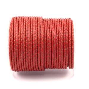 May include: A spool of red braided leather cord. The cord is tightly wound and has a smooth, polished finish.