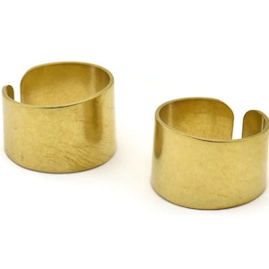 May include: Two gold-colored metal rings. The rings are wide and have a smooth, slightly textured surface.