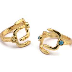 May include: Two gold rings with a turquoise stone set in each. The rings are designed in a unique, abstract shape.