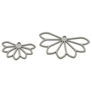 May include: Two silver-coloured, openwork metal charms in a floral design. One charm is smaller than the other. Each charm has a small loop at the top for attaching to jewellery. The charms are on a white background.