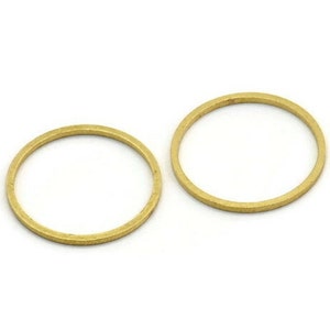 Può includere: Due anelli in metallo color oro, ciascuno con una superficie liscia e arrotondata. Gli anelli sono di dimensioni leggermente diverse.