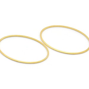 May include: Two gold oval hoops, each with a smooth, polished finish. The hoops are simple and elegant, perfect for adding a touch of sophistication to any outfit.