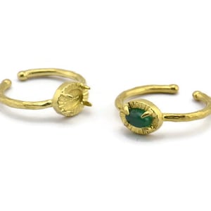 Peut inclure: Deux bagues en or avec une finition texturée. Une bague a une pierre précieuse verte sertie au centre, tandis que l'autre bague a un sertissage vide.