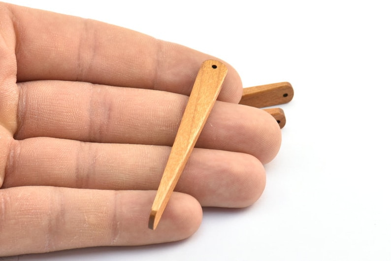 May include: A set of three wooden dowel rods with a pointed tip. The dowels are light brown in color and have a smooth finish.