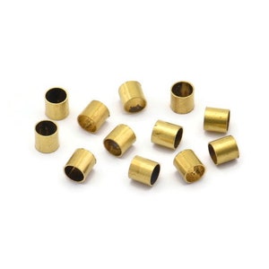 May include: A group of 12 gold-colored metal tube crimp beads. The beads are about 1/2 inch long and have a smooth, shiny finish.