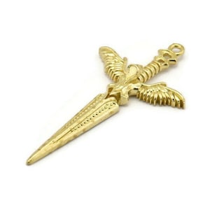 Puede incluir: Pendiente de metal dorado con forma de espada estilizada con alas. La espada tiene una punta afilada y un diseño detallado.