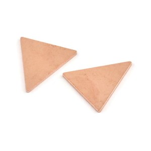 May include: Two copper triangle shapes, each with a slightly different texture, are shown against a white background.