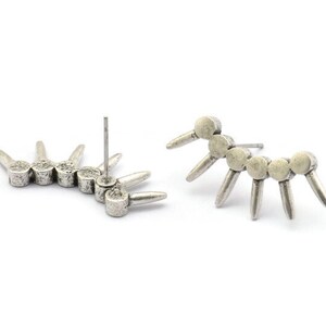 May include: A pair of silver earrings with a geometric design. Each earring features a row of small, round silver beads with pointed spikes extending out from the beads.