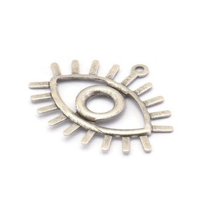 May include: Silver charm in the shape of an eye with a circle in the center. The eye has a detailed design with rays emanating from it.