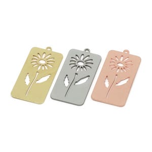 May include: Three rectangular pendants with a daisy flower cutout design. The pendants are in gold, silver, and rose gold colors. Each pendant has a small loop at the top for hanging.