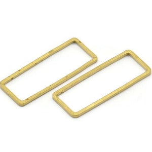 Könnte beinhalten: Zwei rechteckige goldfarbene Metallringe. Die Ringe sind offen und haben eine glatte, leicht strukturierte Oberfläche.