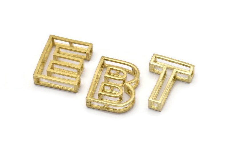 Pu&ograve; includere: Lettere in metallo dorato che compongono la parola "EBT" in uno stile moderno e geometrico. Ogni lettera &egrave; composta da pi&ugrave; quadrati sovrapposti.