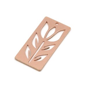 Può includere: Un ciondolo rettangolare in metallo color oro rosa con un design floreale traforato. Il ciondolo presenta uno stelo con foglie e una forma di fiore nella parte superiore. Ha un piccolo foro nella parte superiore per il fissaggio a gioielli o altri lavori artigianali.