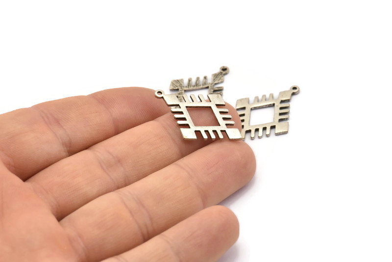 May include: Three silver metal charms in the shape of a square with an inner square. The charms have a geometric design and are perfect for jewelry making.